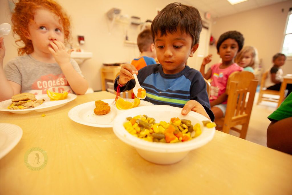 Young children eating and serving food in a classroom